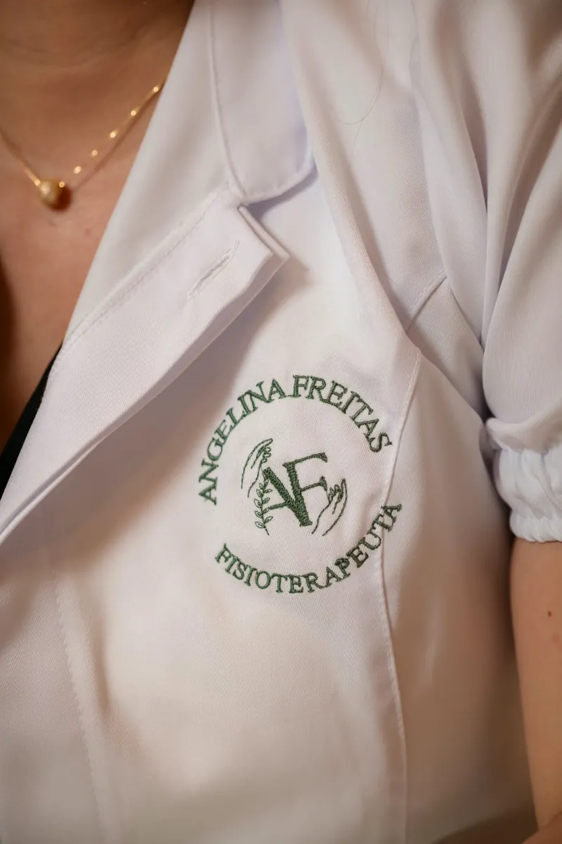 Detalhe do jaleco branco com a logo bordada de Angelina Freitas, fisioterapeuta